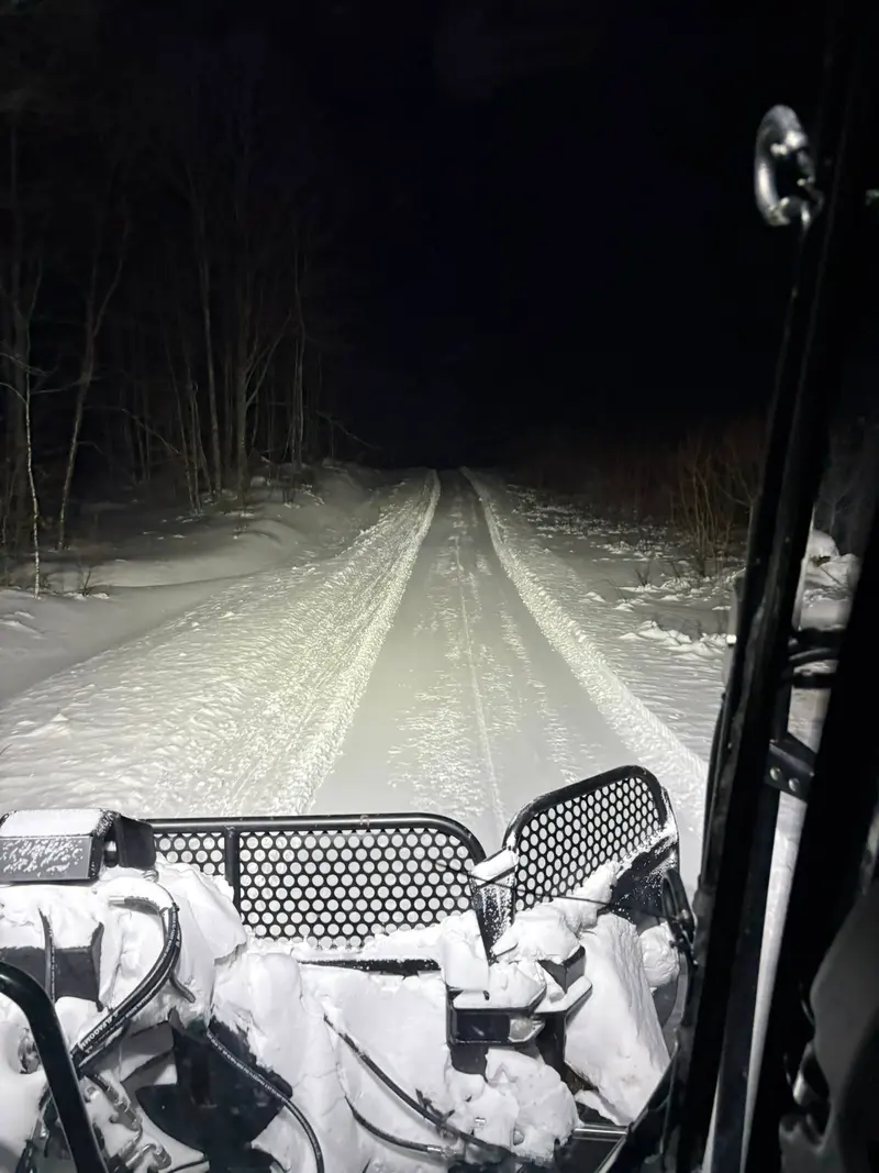 View from inside the groomer looking down a freshly groomed trail at night